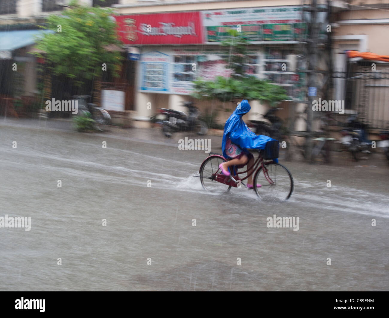 Frau Radfahrer gefangen im Monsun-Regen-Regen in Hue, Vietnam Stockfoto