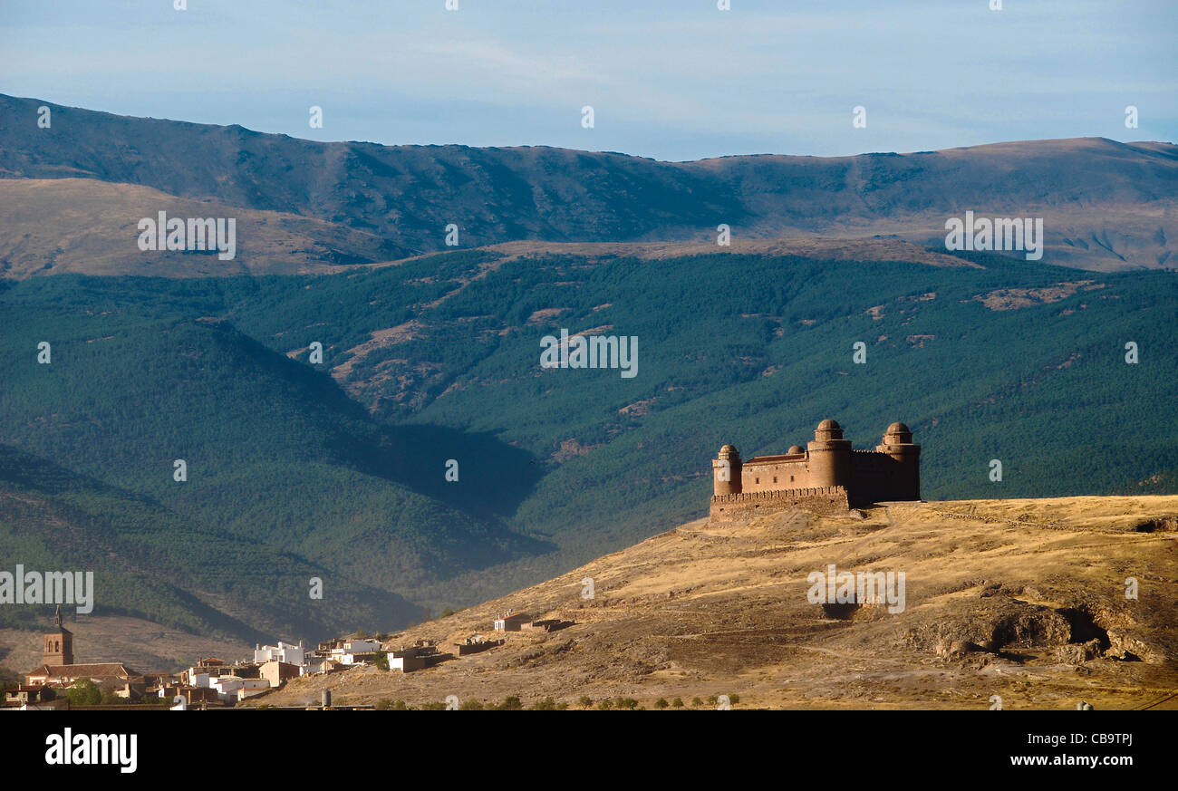 Castillo De La Calahorra (Schloss La Calahorra) sitzt majestätisch auf einem Hügel über der Stadt, der Sierra Nevada im Hintergrund. Stockfoto