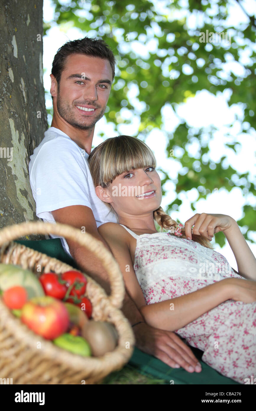 Paar saß Baum mit Korb mit frischen Produkten Stockfoto