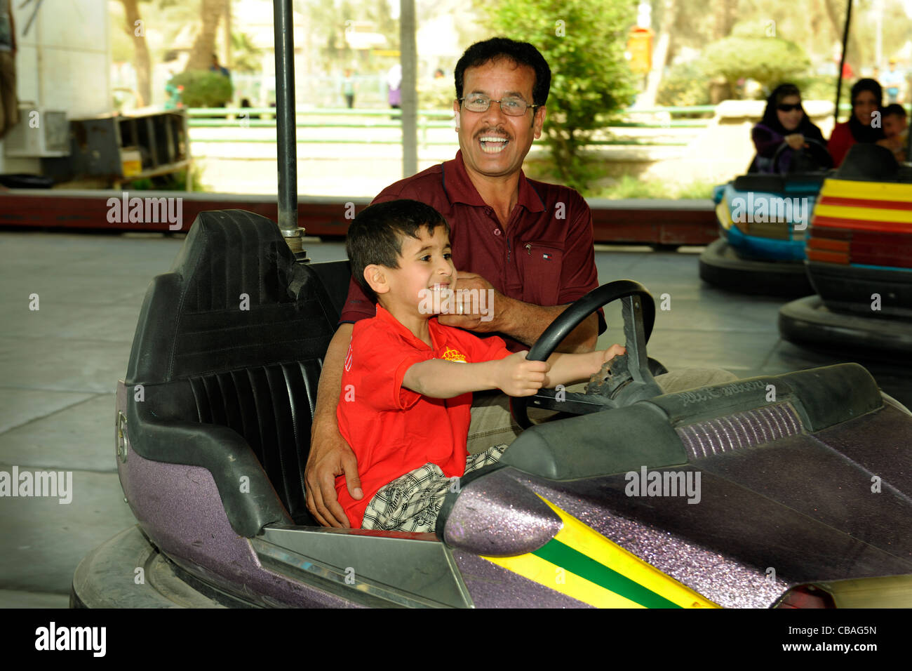 Irak, Baghdad. Vater und Sohn fahren Autoscooter im Freizeitpark Haswa Stockfoto