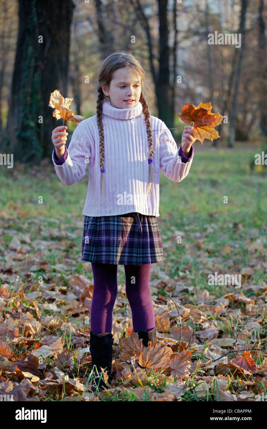 Mädchen spielt im Wald mit Herbstlaub Stockfoto