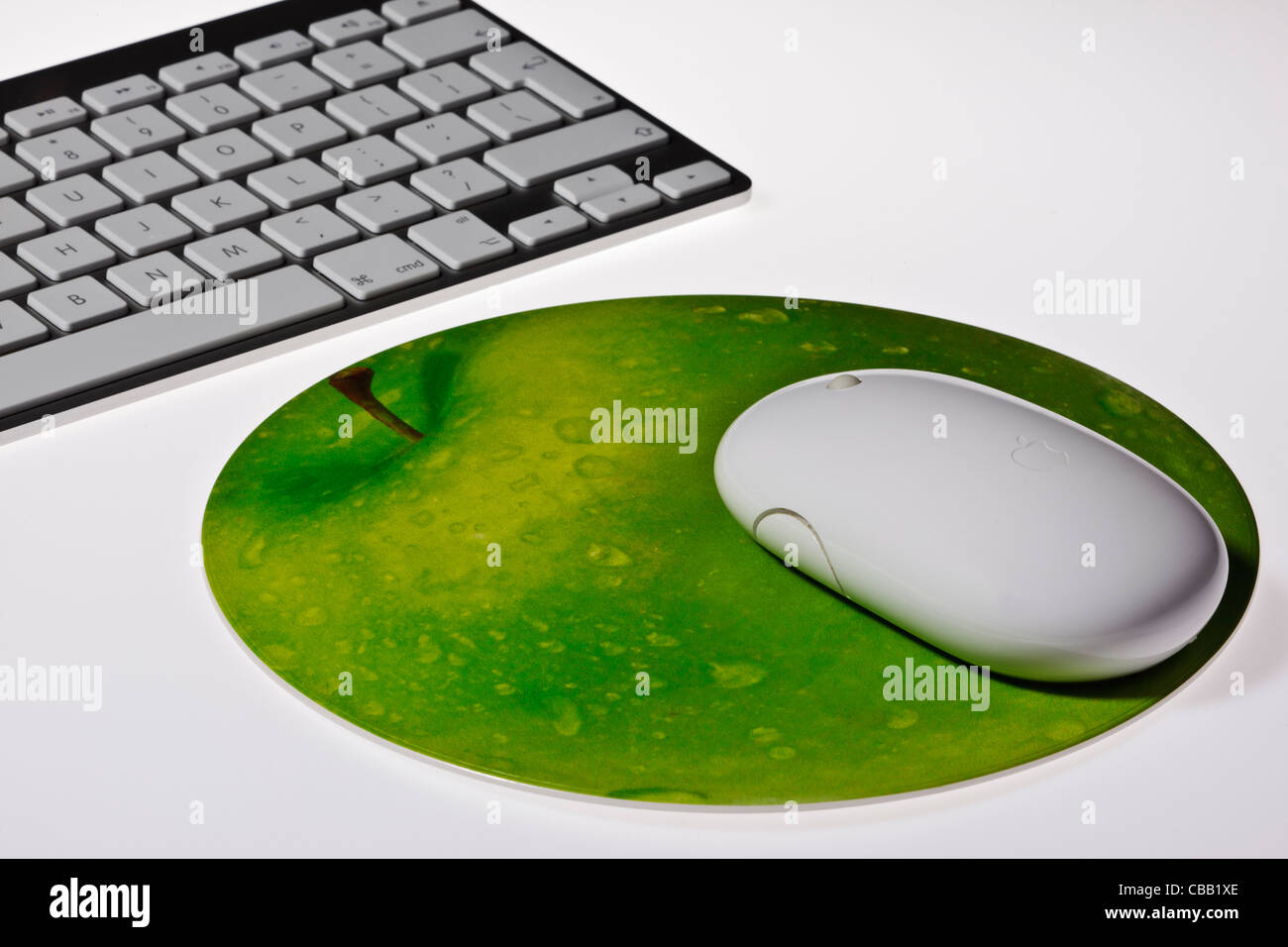 Nahaufnahme von Apple Funkmaus auf einem Mauspad in der Form eines Apfels mit ein Apple wireless Keyboard auf weißem Hintergrund Stockfoto