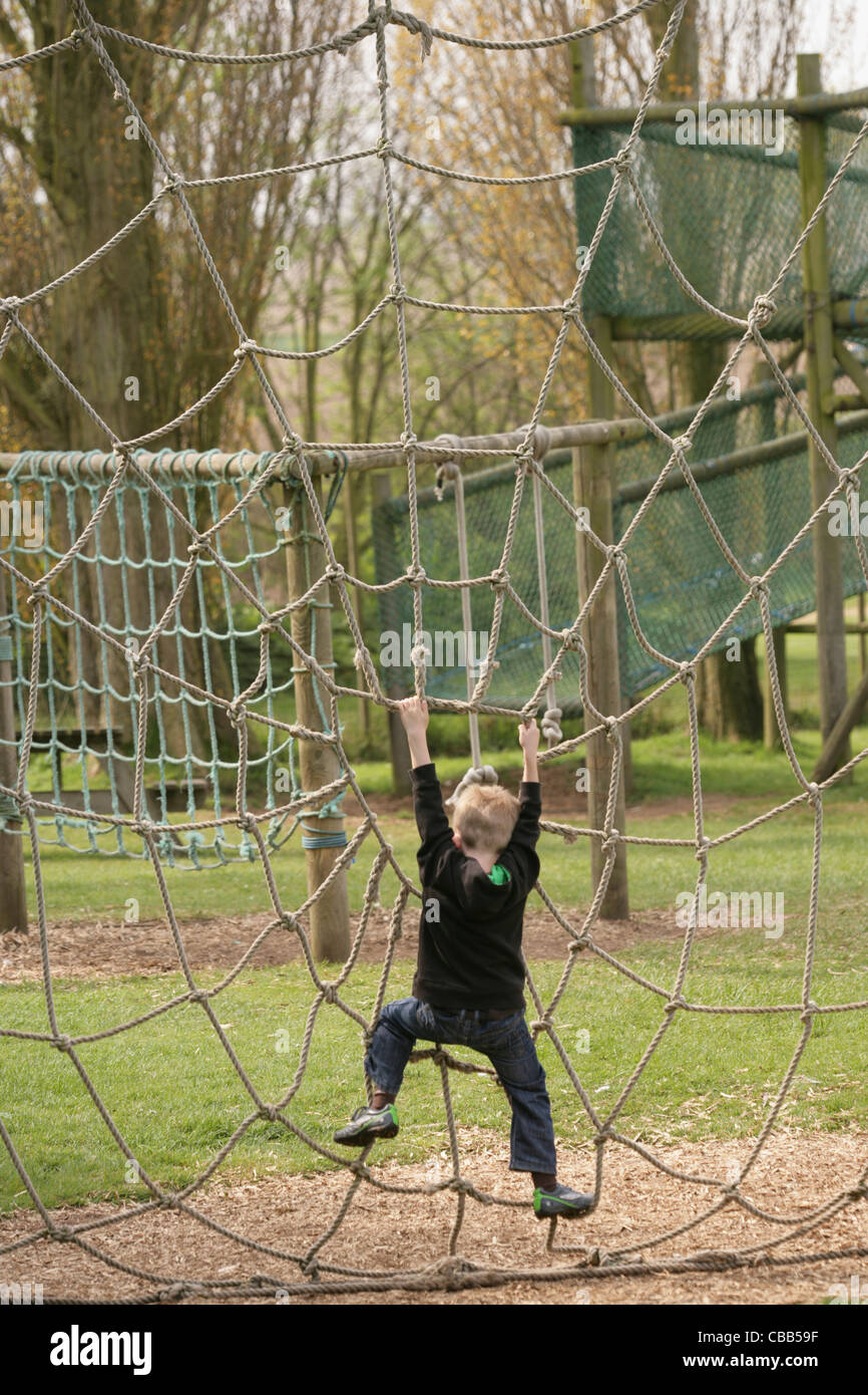 Junge Kind spielen an einem Spinnennetz Seil. Spielplatz, Thrigby Hall Wildlife Gardens, Filby, Great Yarmouth, Norfolk. Stockfoto