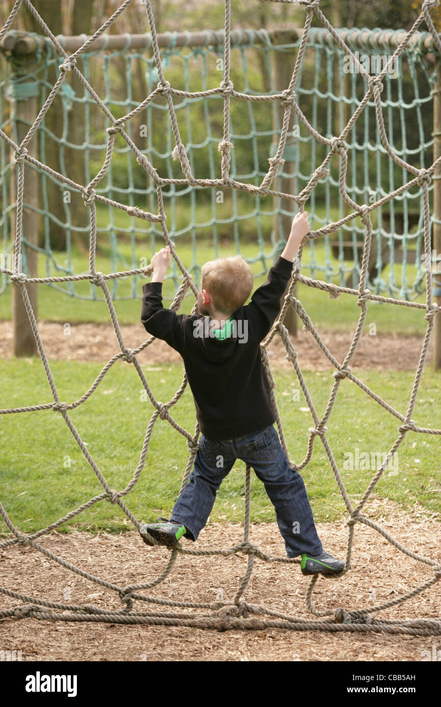 Junge Kind spielen an einem Spinnennetz Seil. Spielplatz, Thrigby Hall Wildlife Gardens, Filby, Great Yarmouth, Norfolk. UK. Stockfoto