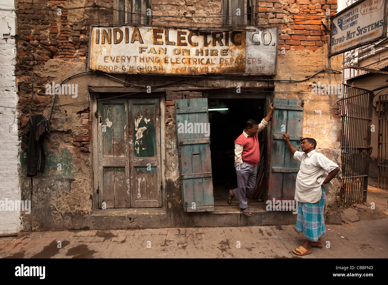 Indien, Westbengalen, Kolkata, Chowringhee, Suddar Street, Männer sprechen außerhalb alte altmodische Geschäftsräume Stockfoto