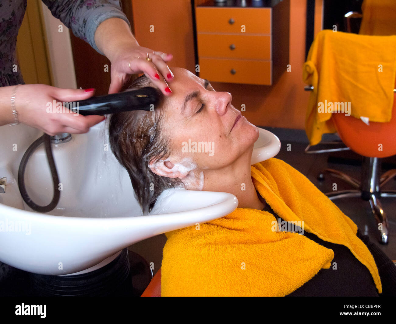 Frau mittleren Alters, die ihr Haar gewaschen in den Friseursalon Stockfoto