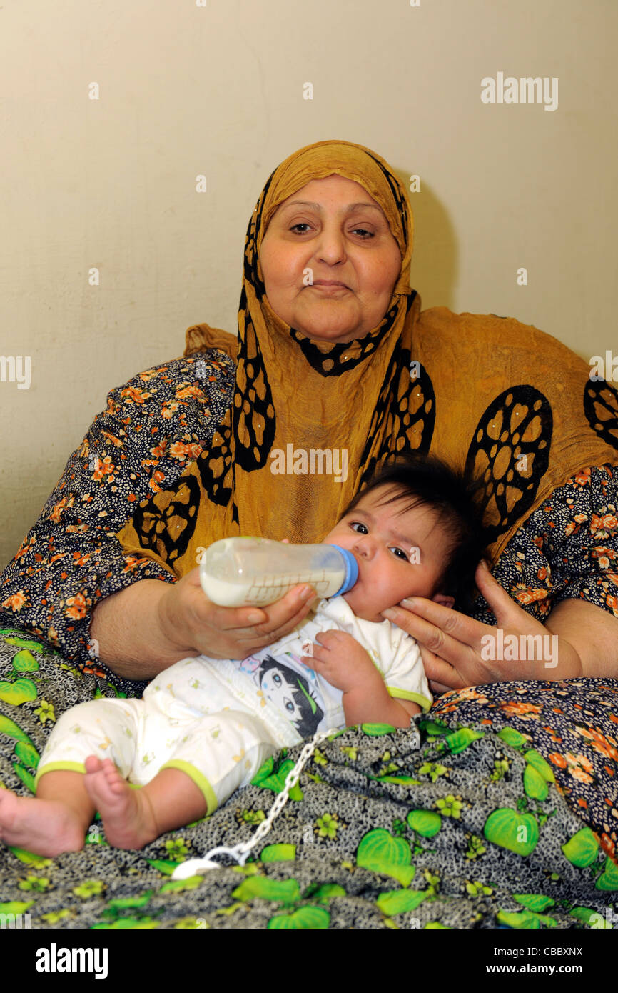 Irak, Baghdad. Eine irakische Großmutter von einer Granate in der 2003-Krieg verletzten füttert ihr grand Kind Stockfoto