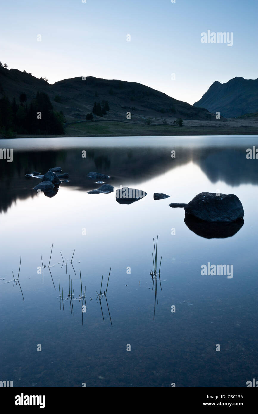 Felsen und Reflexionen bei Dämmerung, Blea Tarn, Lake District, Cumbria Stockfoto