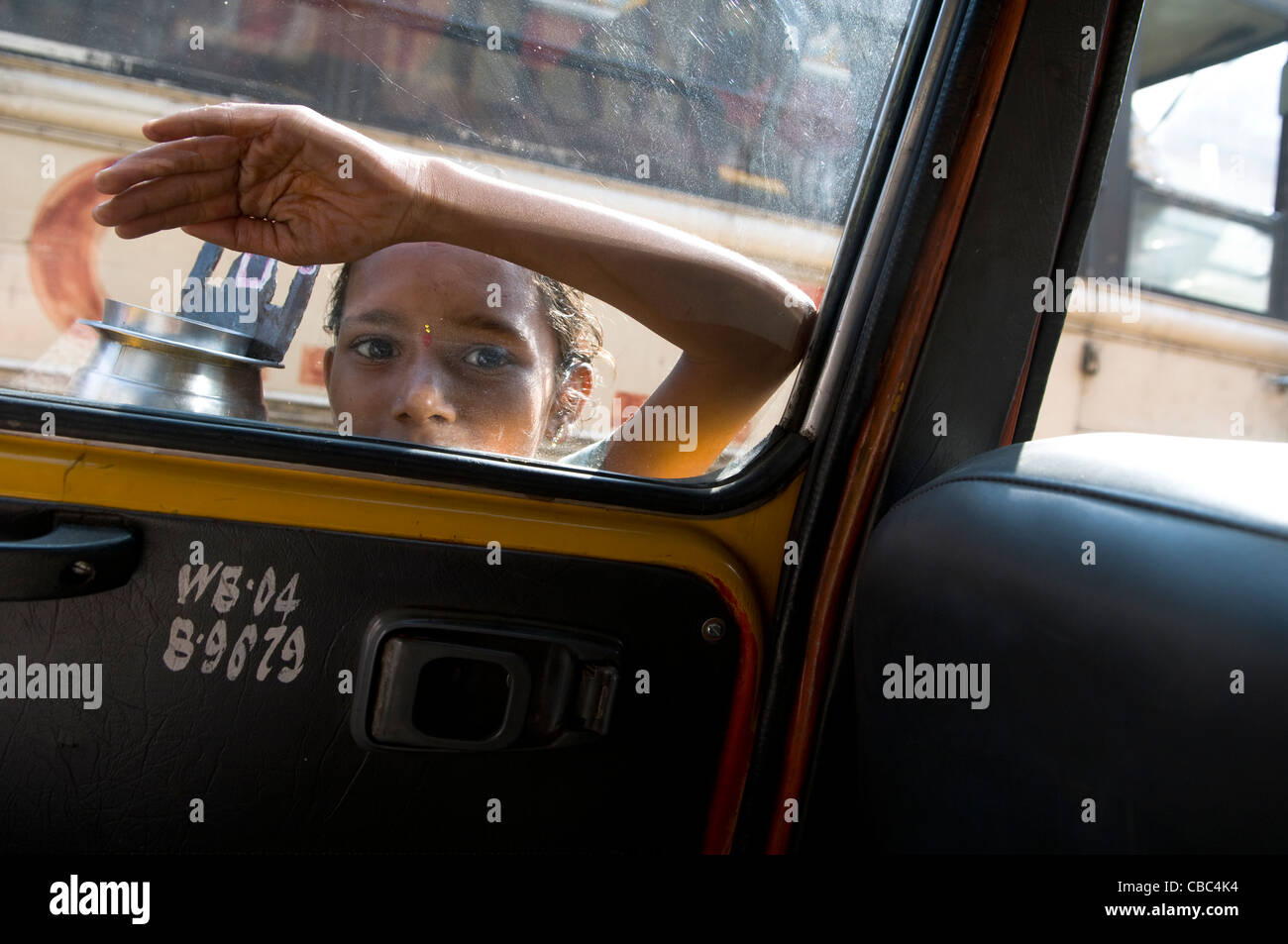 Ein junger Bettler klopfen am Fenster und Taxis auf einer belebten Straße in Kalkutta. Stockfoto