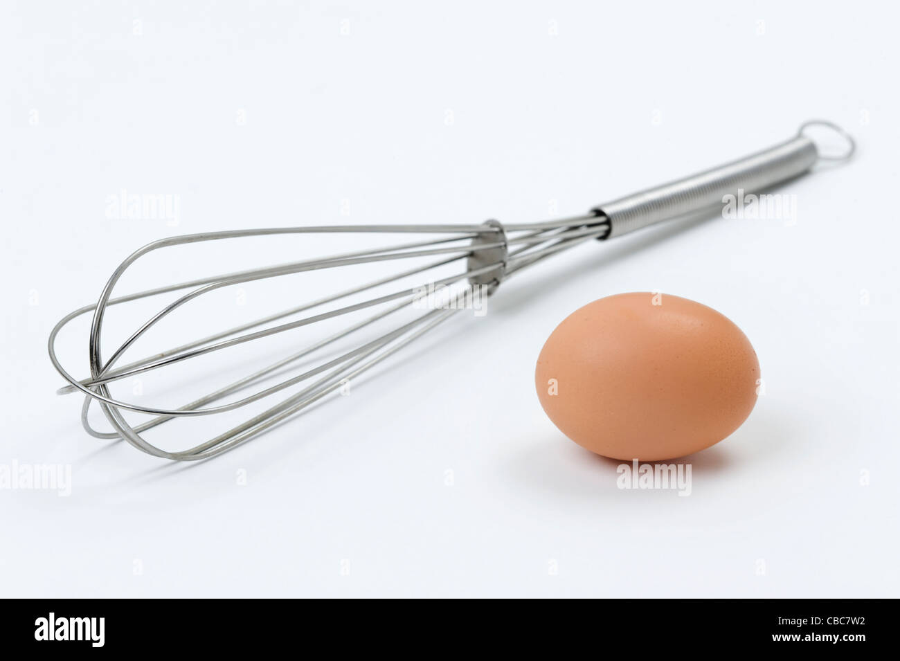 ein einzelnes Ei mit einem Schneebesen Edelstahl vor einem weißen Hintergrund Stockfoto