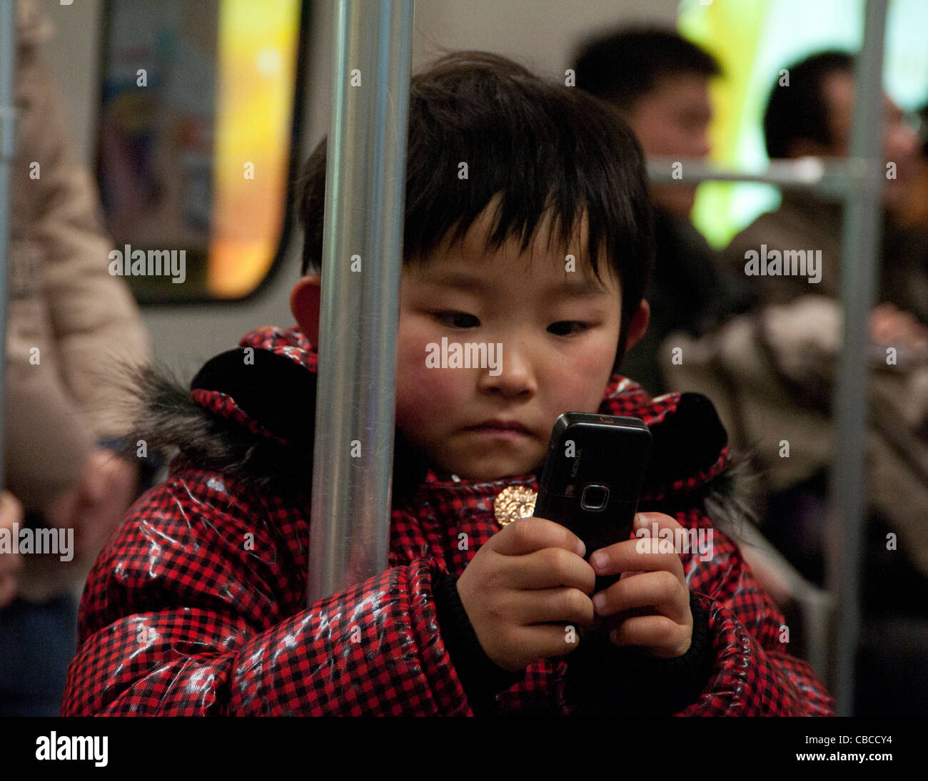 Pre-Schooler in Zeile 2 der Metro Shanghai, China, Handy, Smarphone, handlich, Konzentration Stockfoto