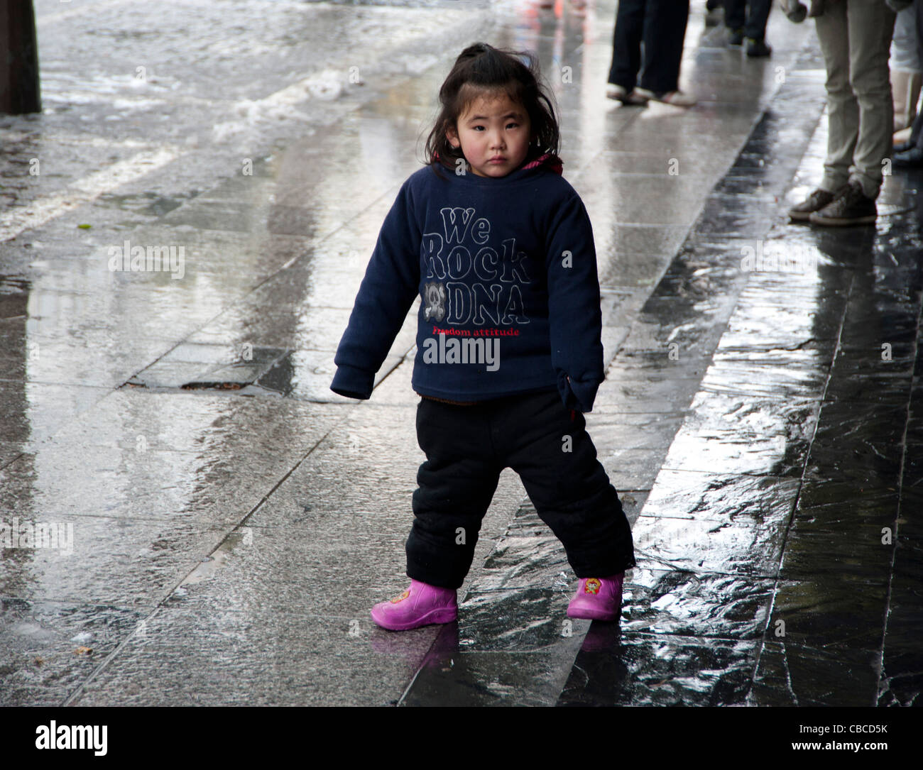 neugierig Pre-Schooler auf nassen Straße in Shanghai, China Stockfoto