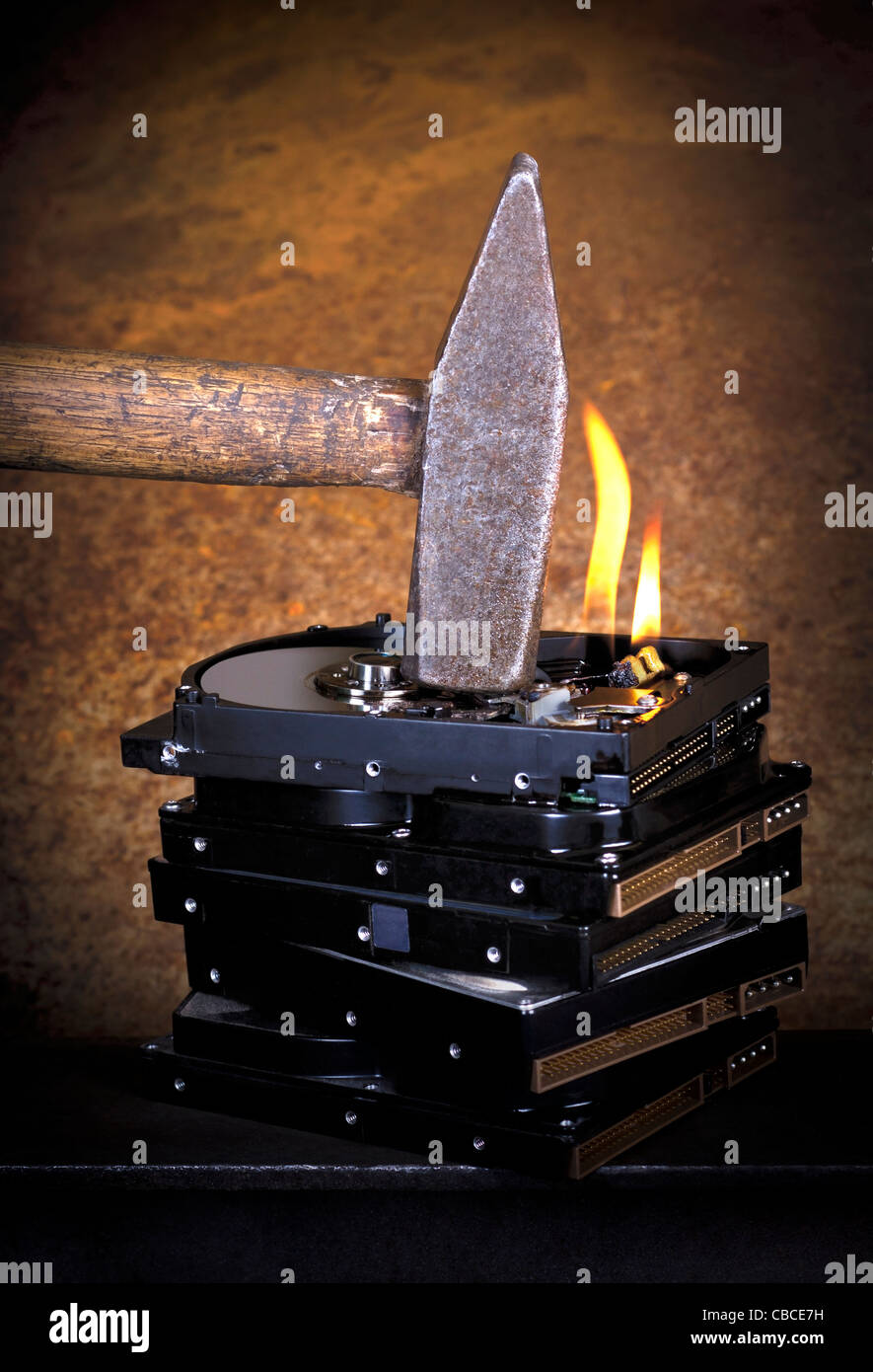 symbolische Daten Zerstörung Thema zeigt die Details eines Hammers auf ein Stapel brennen Festplatten vor rostigen zurück Stockfoto
