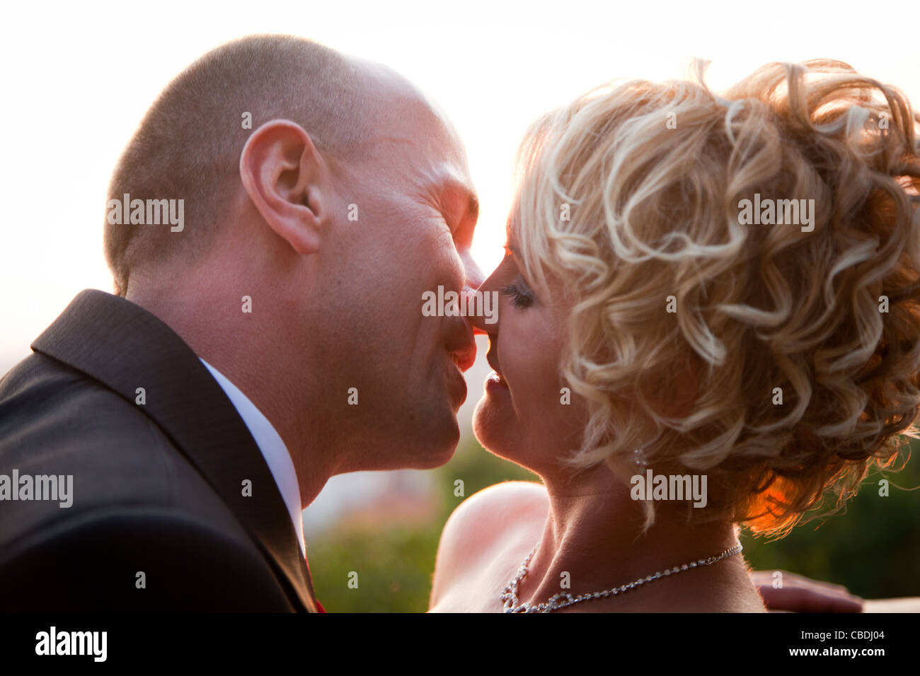 Glückliche Braut und Bräutigam küssen im Freien bei Sonnenuntergang Stockfoto