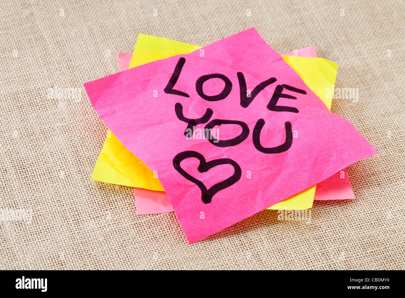 Bürokonzept Romantik - liebe dich Text handschriftlich auf roten Zettel Stockfoto