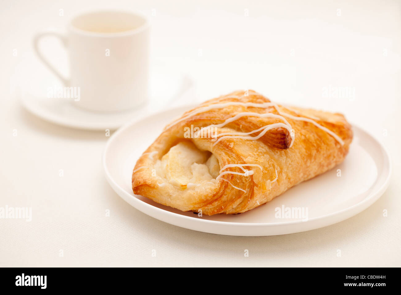 Apple Croissant Gebäck auf weißen Teller mit einer Tasse Espresso-Kaffeemaschine im Hintergrund Stockfoto
