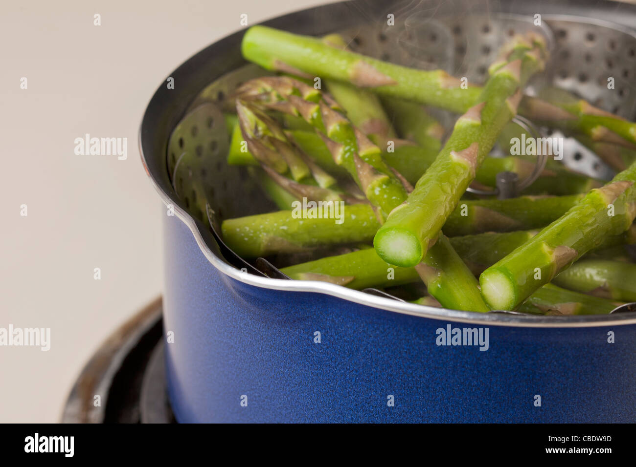 grüner Spargel in einen Dämpfeinsatz in blauen Topf dämpfen Stockfoto