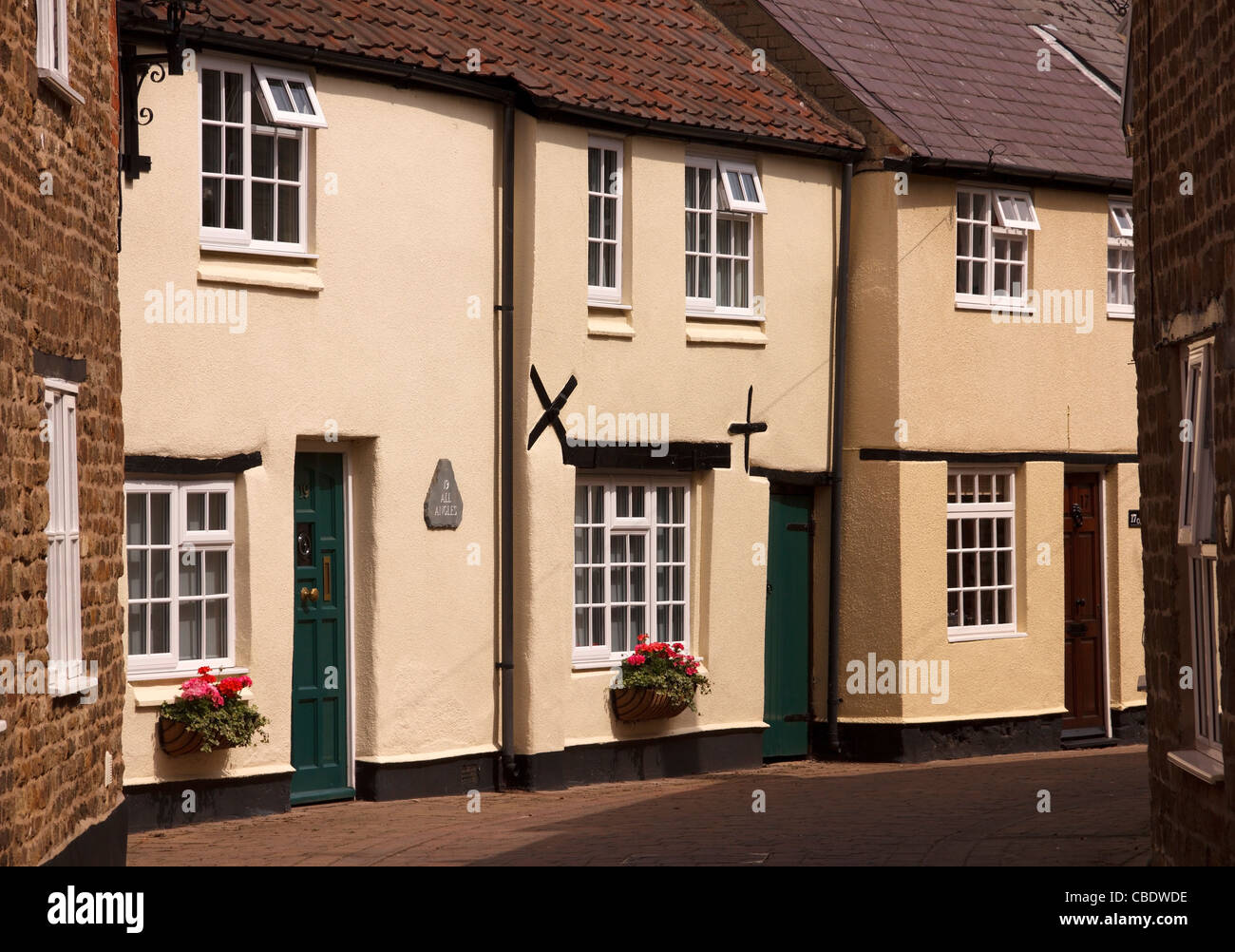 Terrassenförmig angelegten Reihe von schönen alten englischen Cottages in schmalen Seitenstraße, gemalt Deans Street, Oakham, Rutland, England, UK Stockfoto