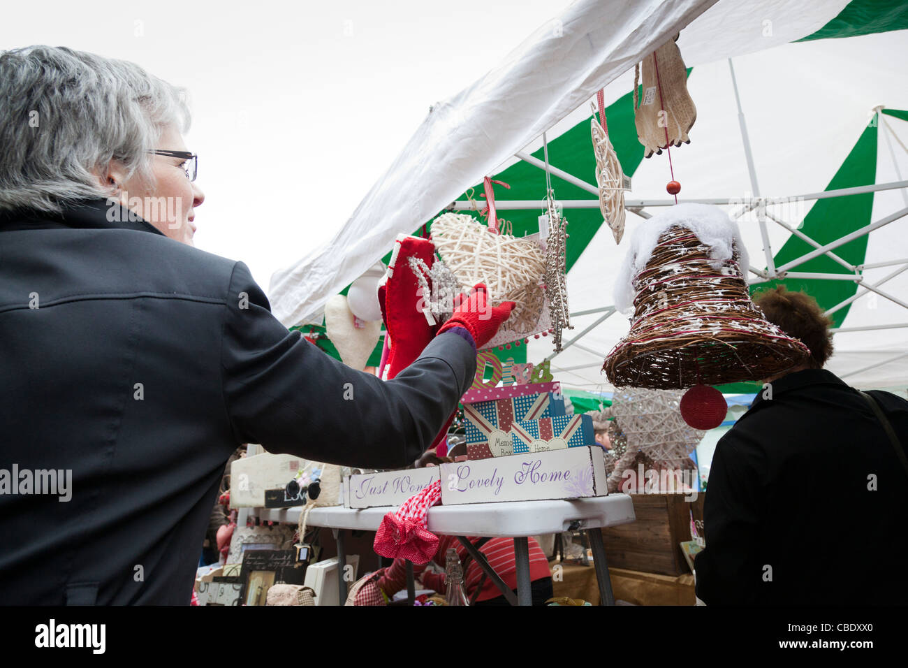 Frau untersucht Weihnachtsschmuck auf einem Marktstand Weihnachten. Stockfoto