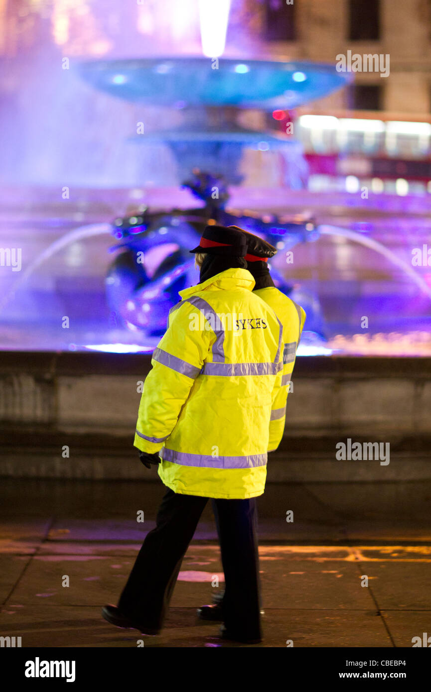 Trafalgar Square bei Nacht zeigt die beleuchteten Springbrunnen mit Sicherheitspersonal vorbei Stockfoto