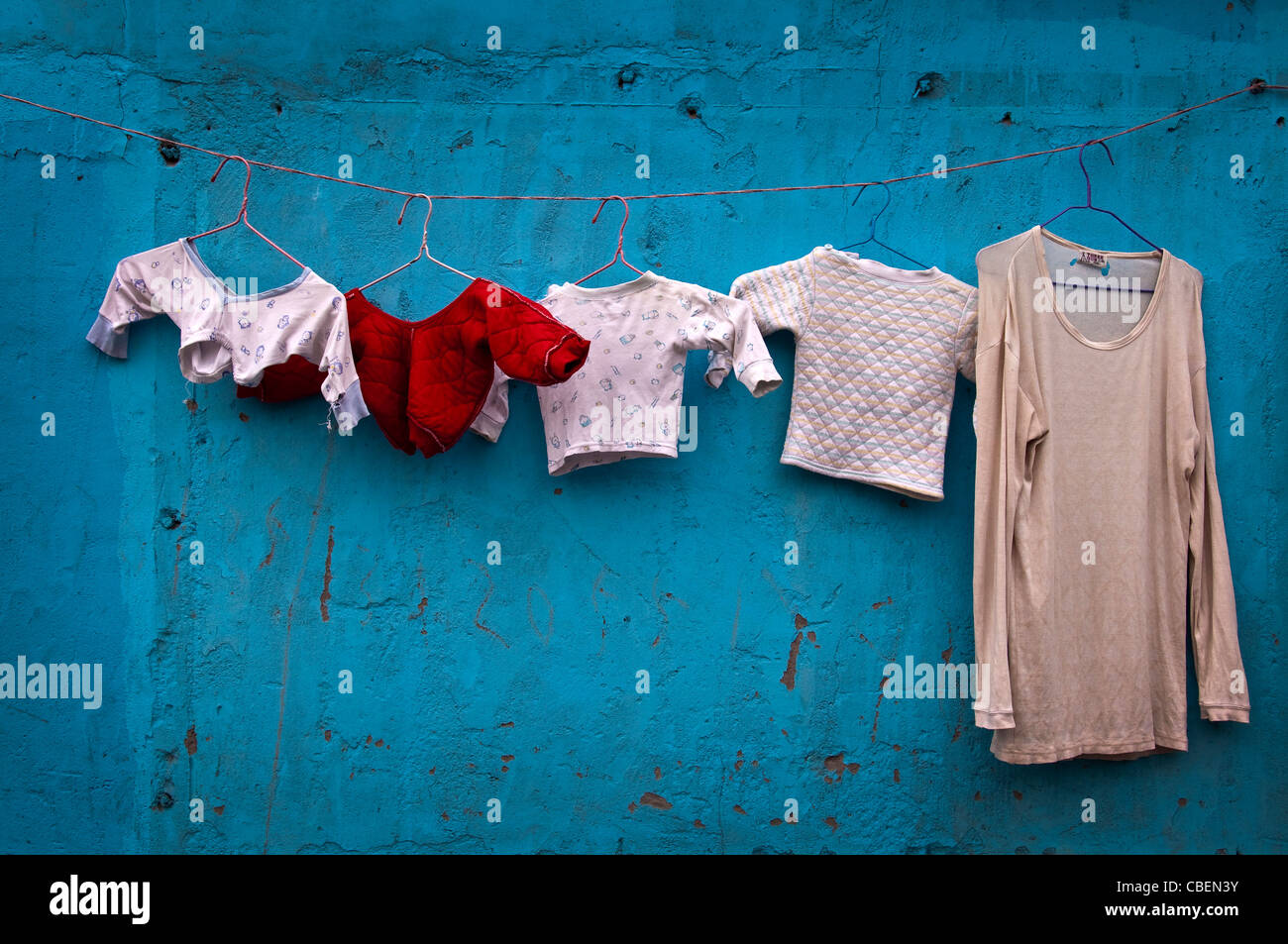 Wäsche hängen in einer Straße vor einer blauen Wand in Shanghai (China) Stockfoto