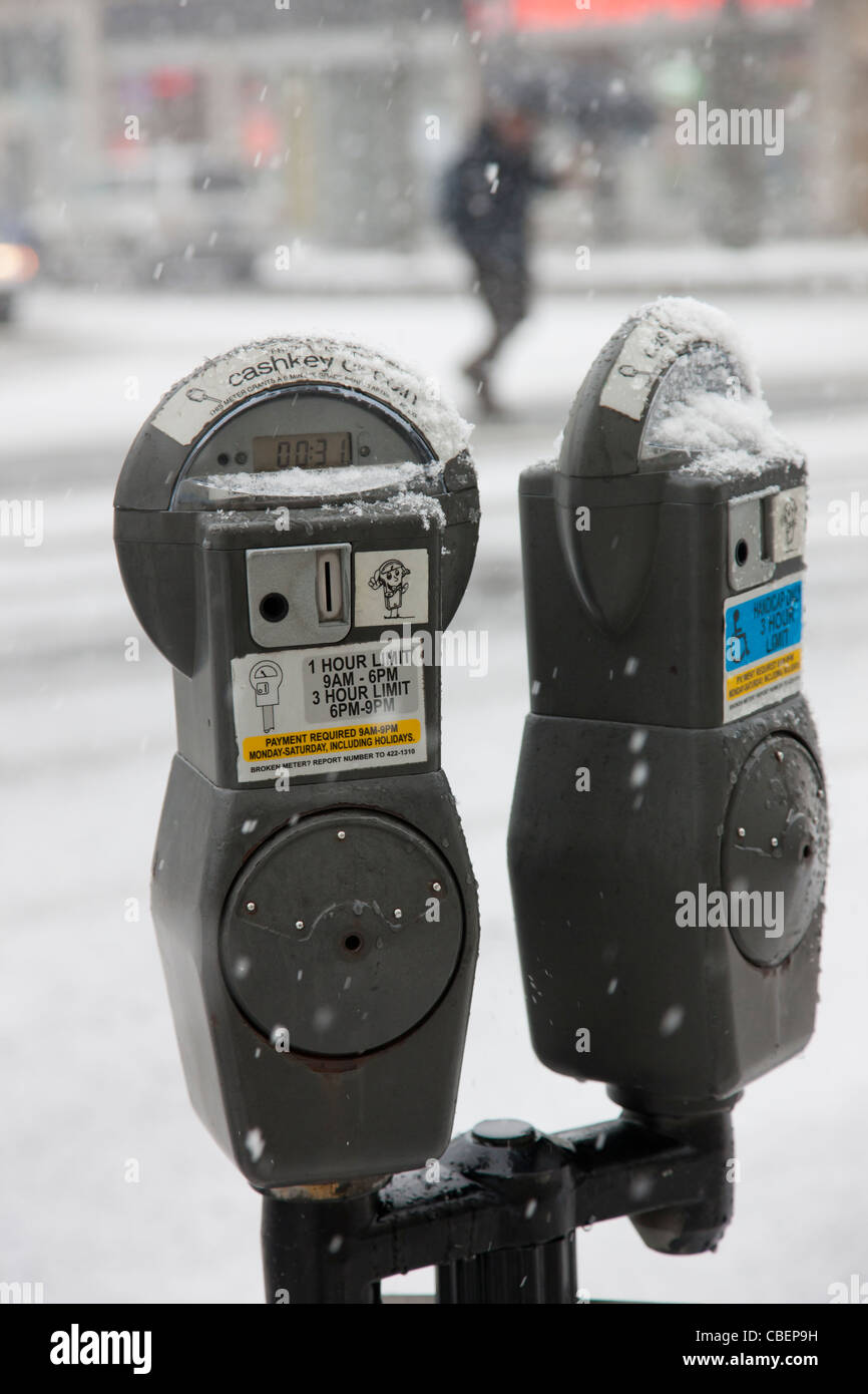 Eine Münze oder Bargeld Taste bedient doppelköpfigen Parkuhr in einem Schneesturm in White Plains, New York. Stockfoto