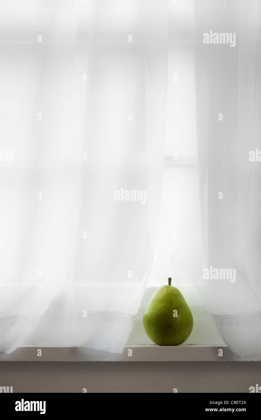 Birne auf Fensterbank mit weißen Vorhang Stockfoto