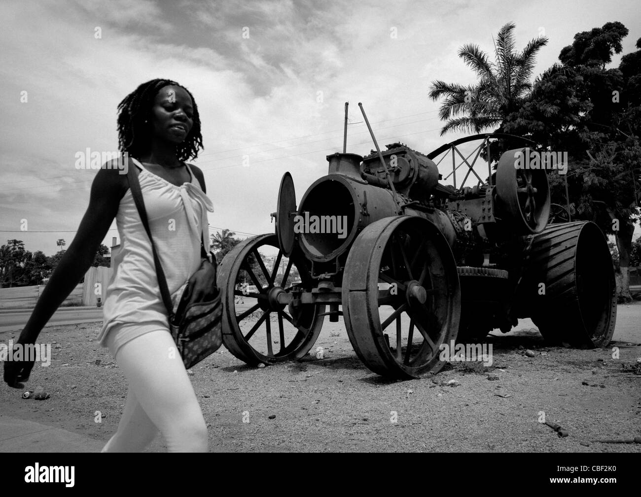 Junge Frau vor einem Traktor Wrack In Lobito, Angola Stockfoto