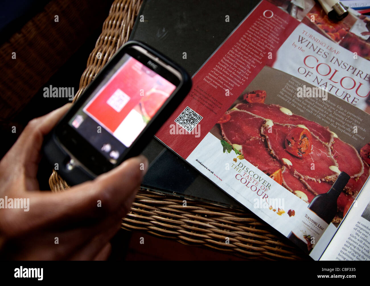 Mit Smartphone mit QR-app zum Erfassen von Quick Response Code im Magazin Werbung, London Stockfoto