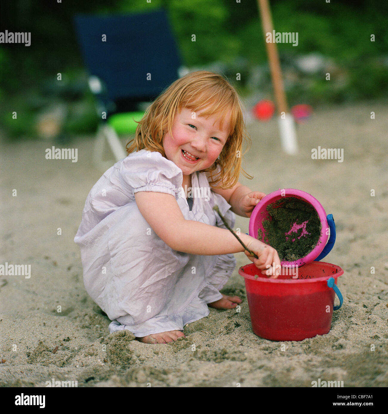 Kleine Mädchen spielen mit einem Eimer am Strand - Kinder spielen im freien Stockfoto