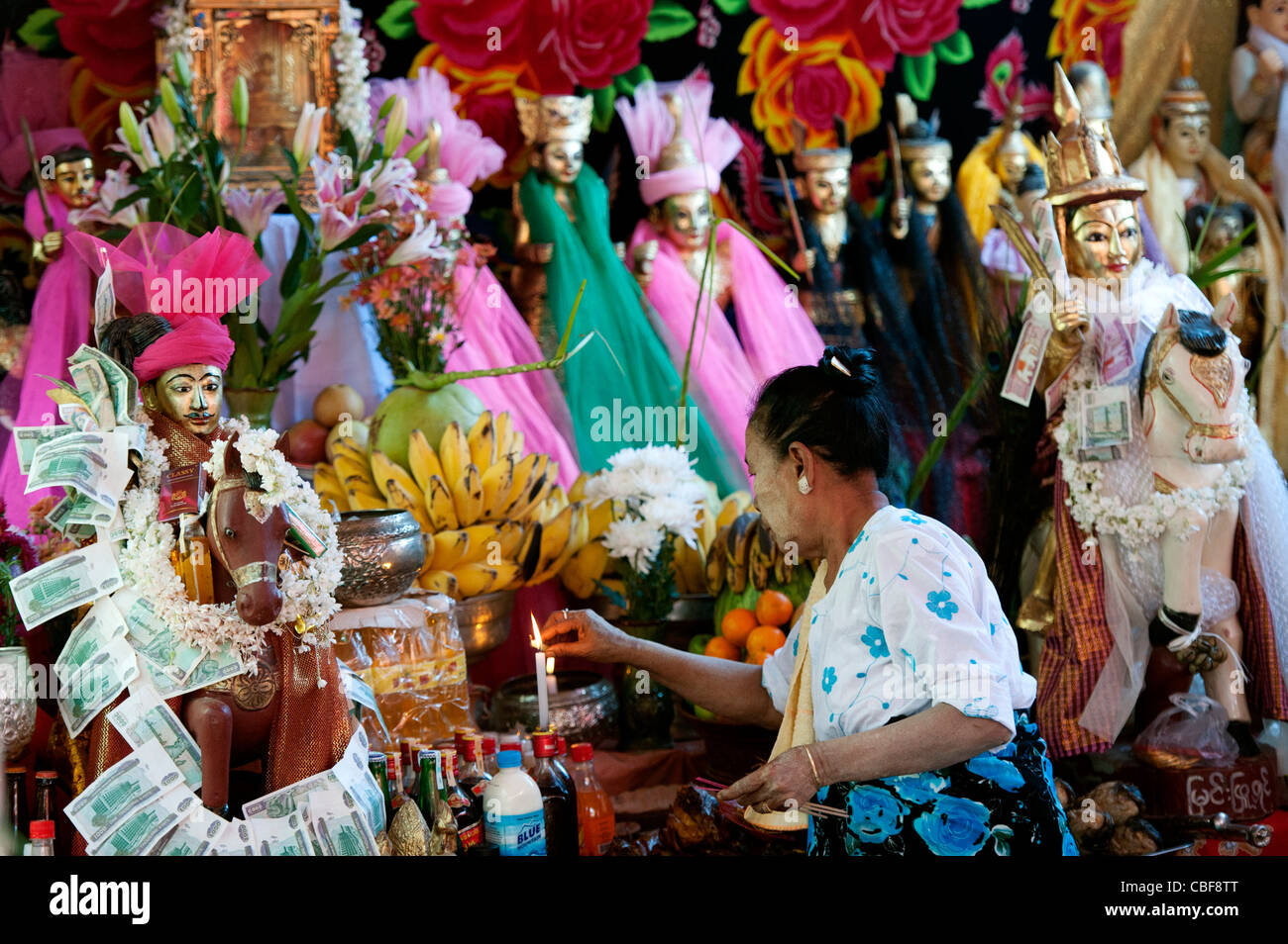 Frau Licht Kerze an Nat-Schrein während Nat Zeremonie, Mandalay, Myanmar (Burma). Stockfoto