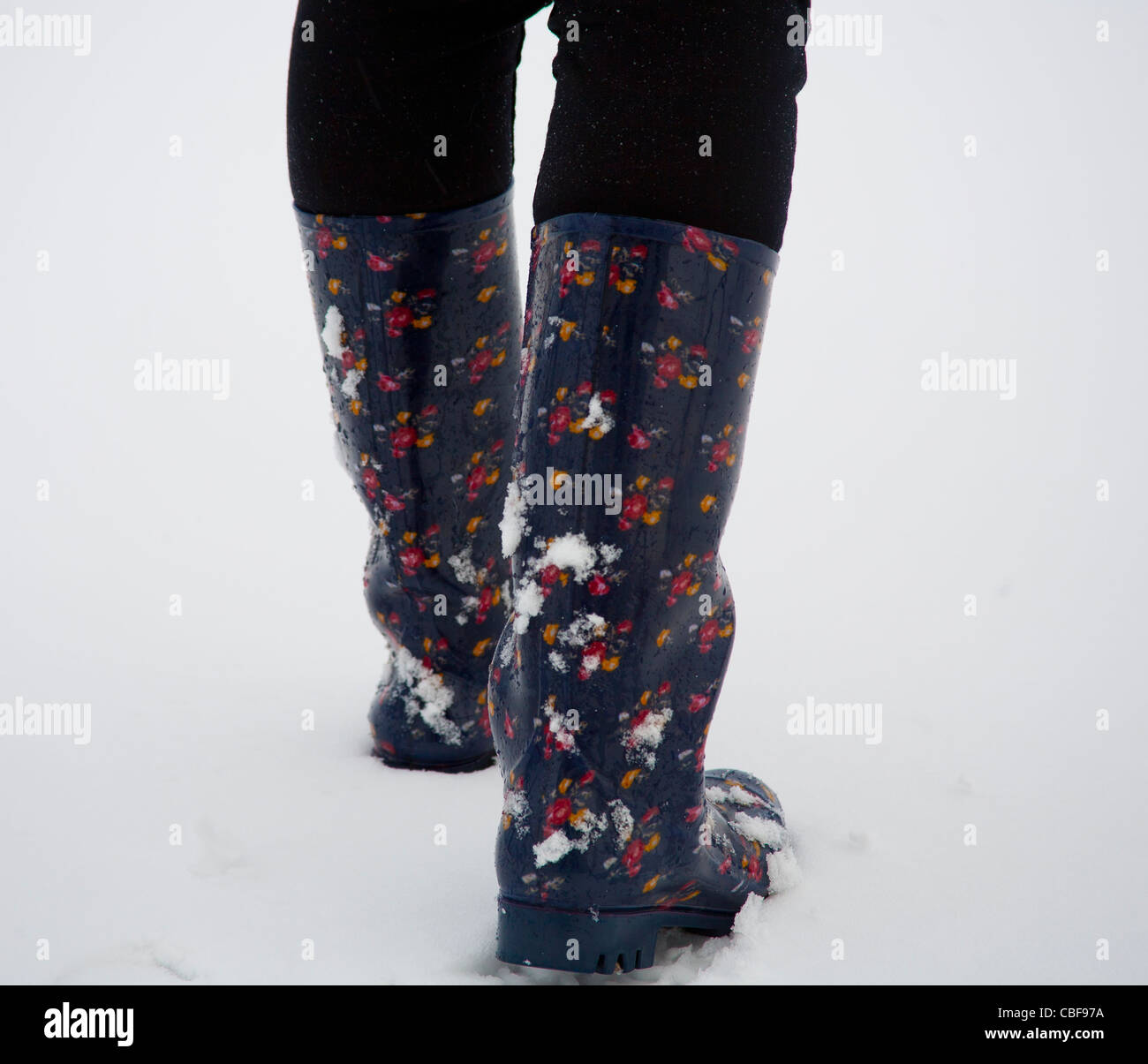 Eine Frau trägt wasserdichte Gummistiefel in Snow Winter Wetter Stockfoto