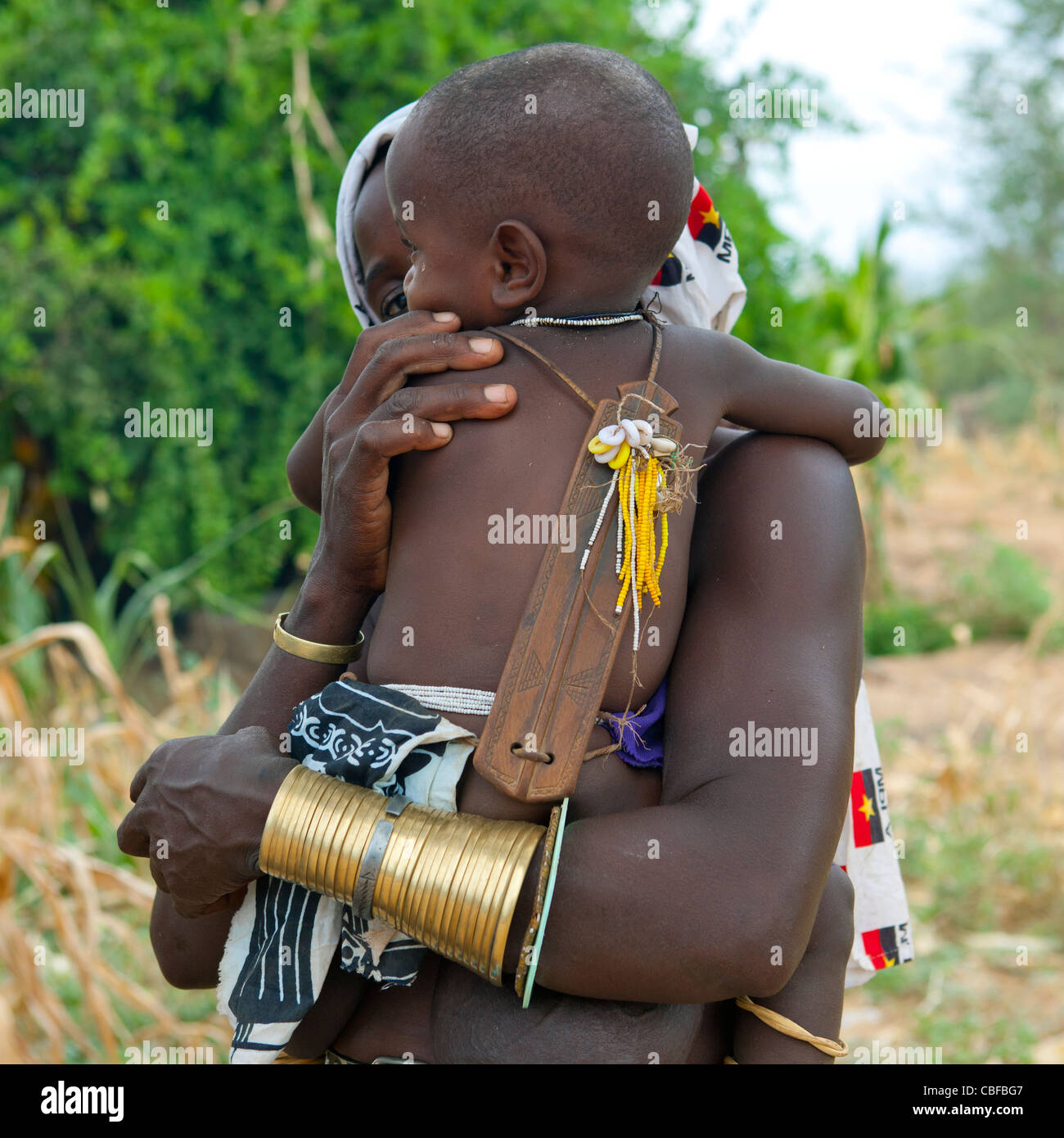 Mucubal Baby mit einer Ombeleketha-Talisman auf der Rückseite In den Armen seiner Mutter, Virie Bereich, Angola Stockfoto