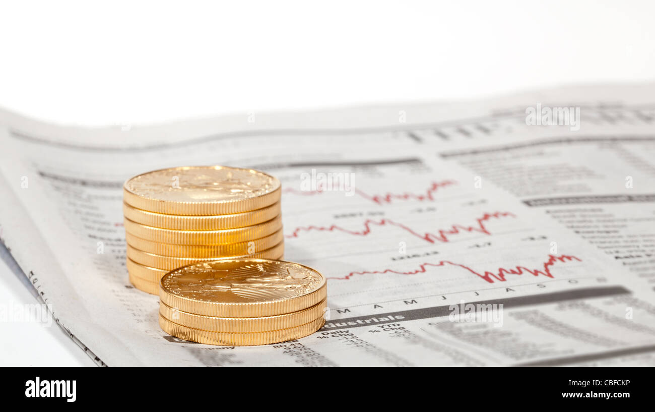 Gold Eagle 1 Unze Münzen gestapelt in Spalten im Wirtschaftsteil der Zeitung mit Diagrammen Stockfoto