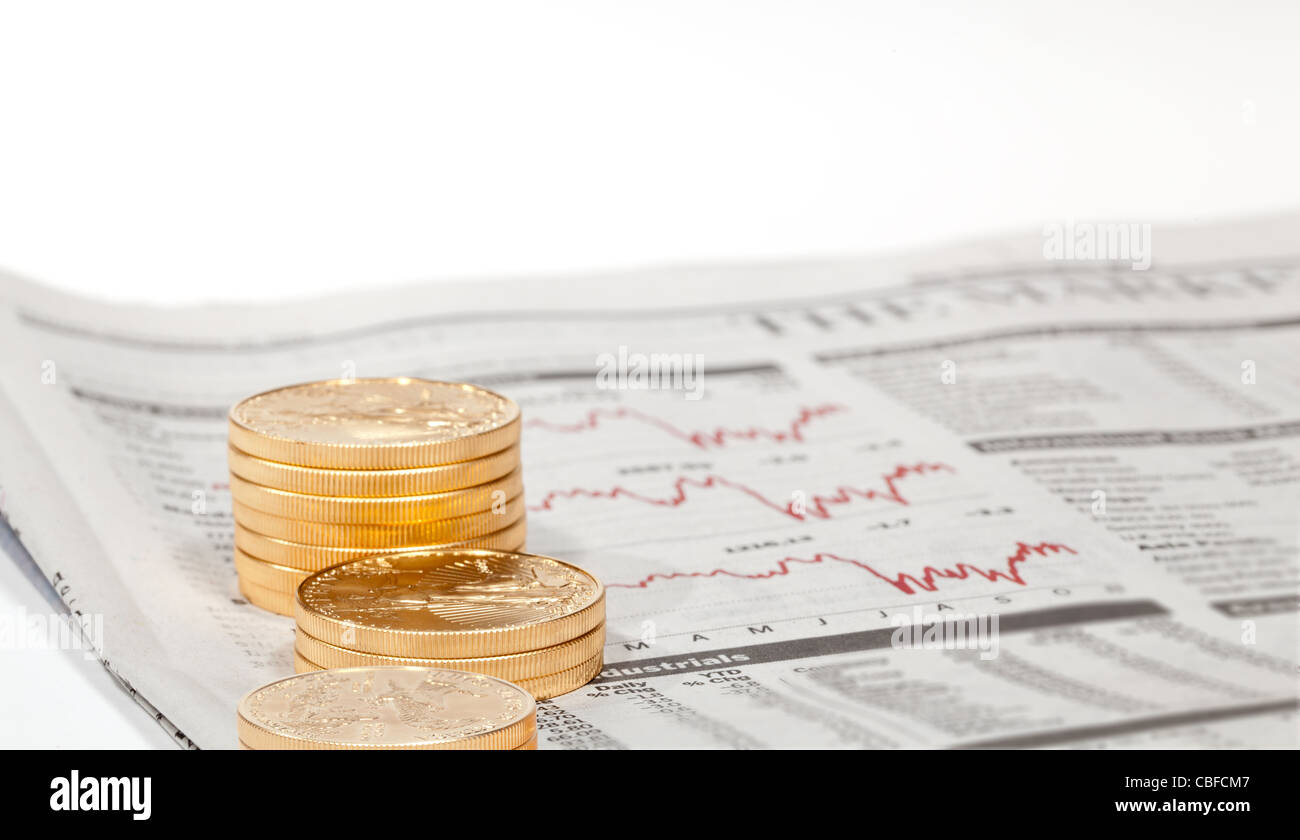 Gold Eagle 1 Unze Münzen gestapelt in Spalten im Wirtschaftsteil der Zeitung mit Diagrammen Stockfoto