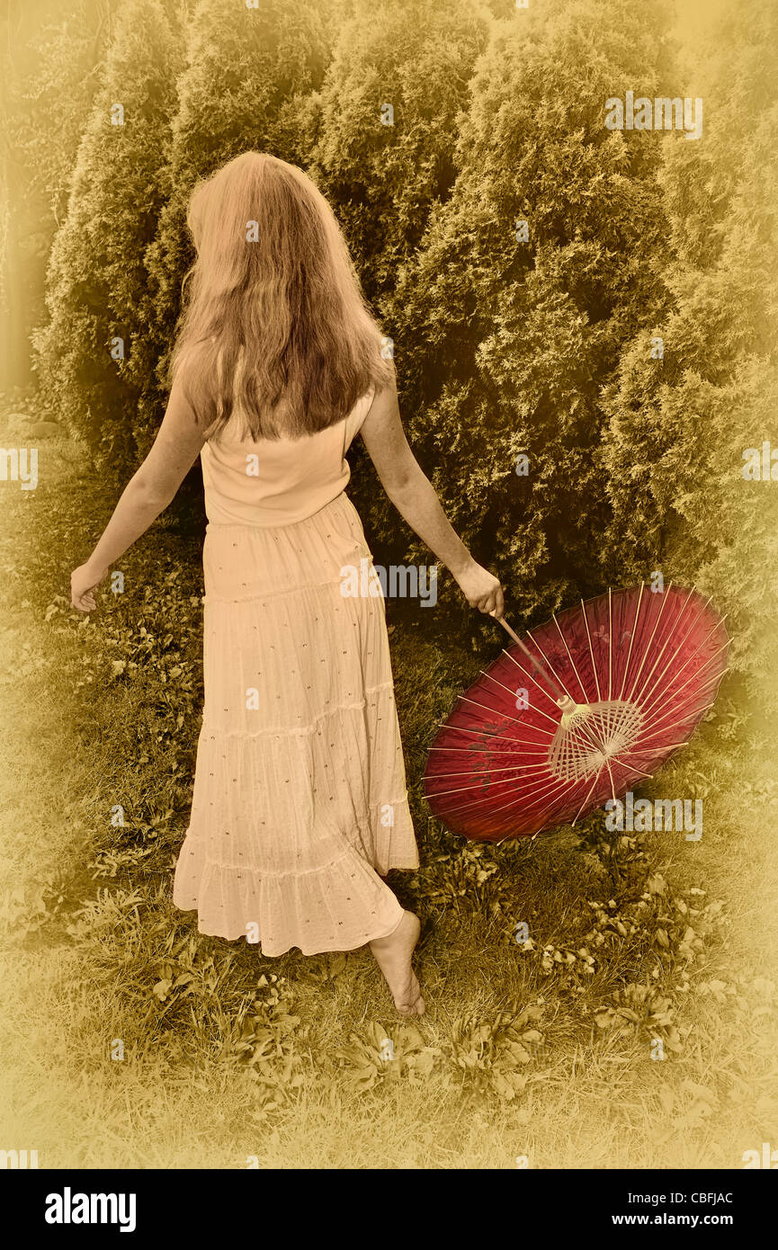 Vignette von hinten Teen Mädchen, die Spaziergänge, schwingen rot Sonnenschirm hinter ihr, lange Rock und ärmelloses Top in antiken Tönungen Stockfoto