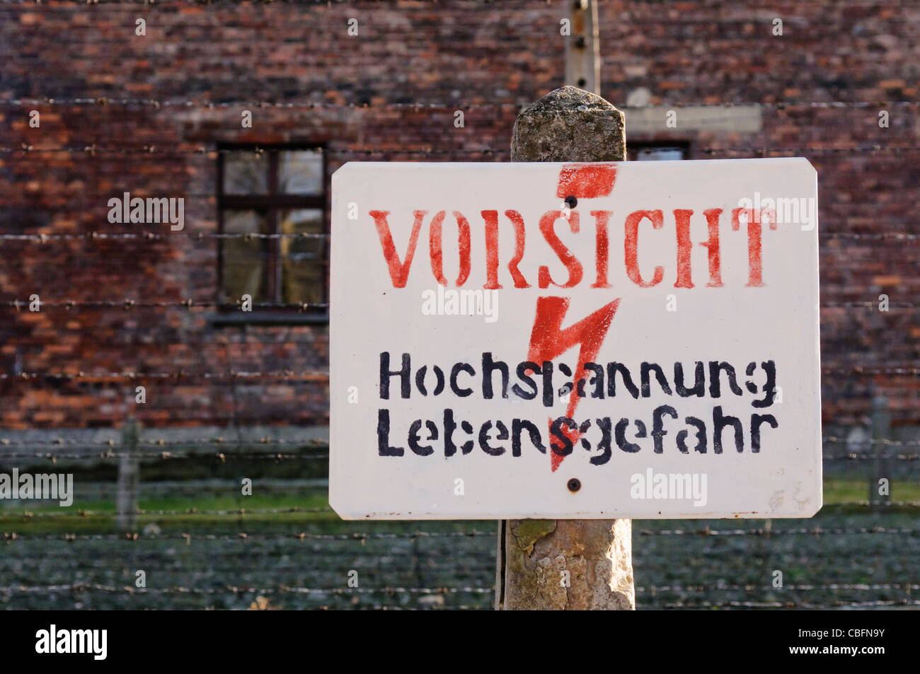 Schild am elektrischen Stacheldrahtzaun in Auschwitz "hochgeliebten: Hochspannung Lebensgefahr" (Gefahr: Hochspannung) Stockfoto