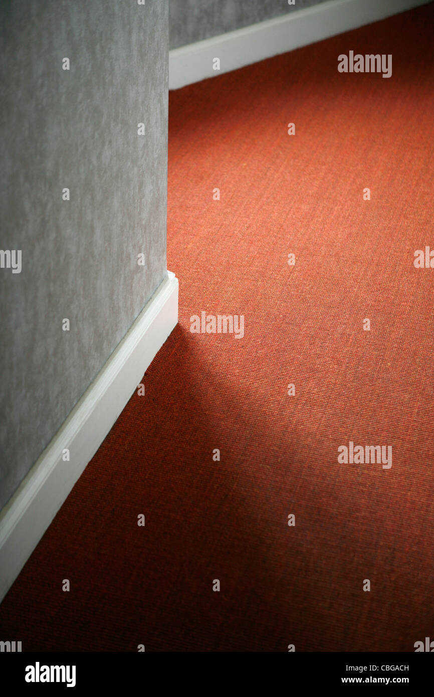 Kontraste der roten Teppich gegen weiße Fußleiste und graue Wand Stockfoto