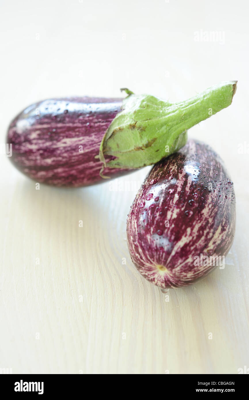 Zwei lila gestreifte Auberginen auf einem Holztisch, einem vertikalen Rahmen Stockfoto