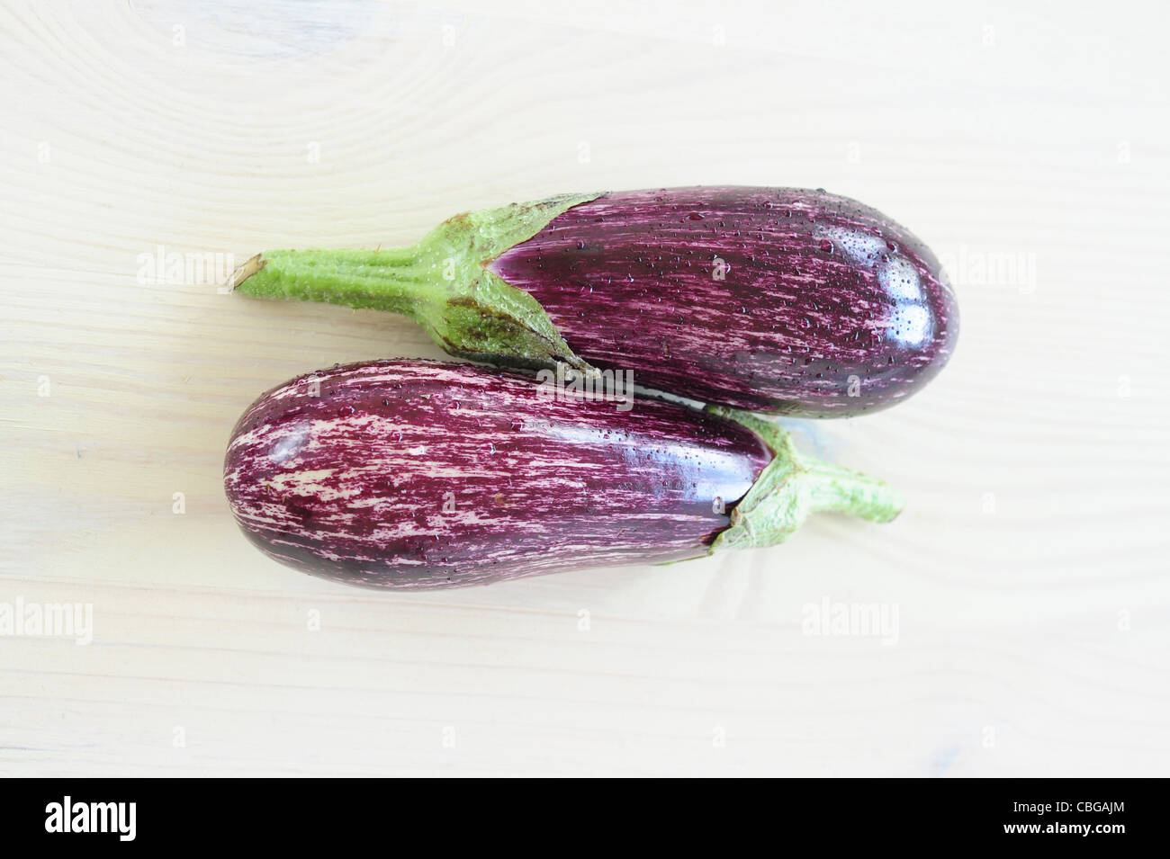 Zwei lila gestreifte Auberginen auf einem Holztisch Stockfoto