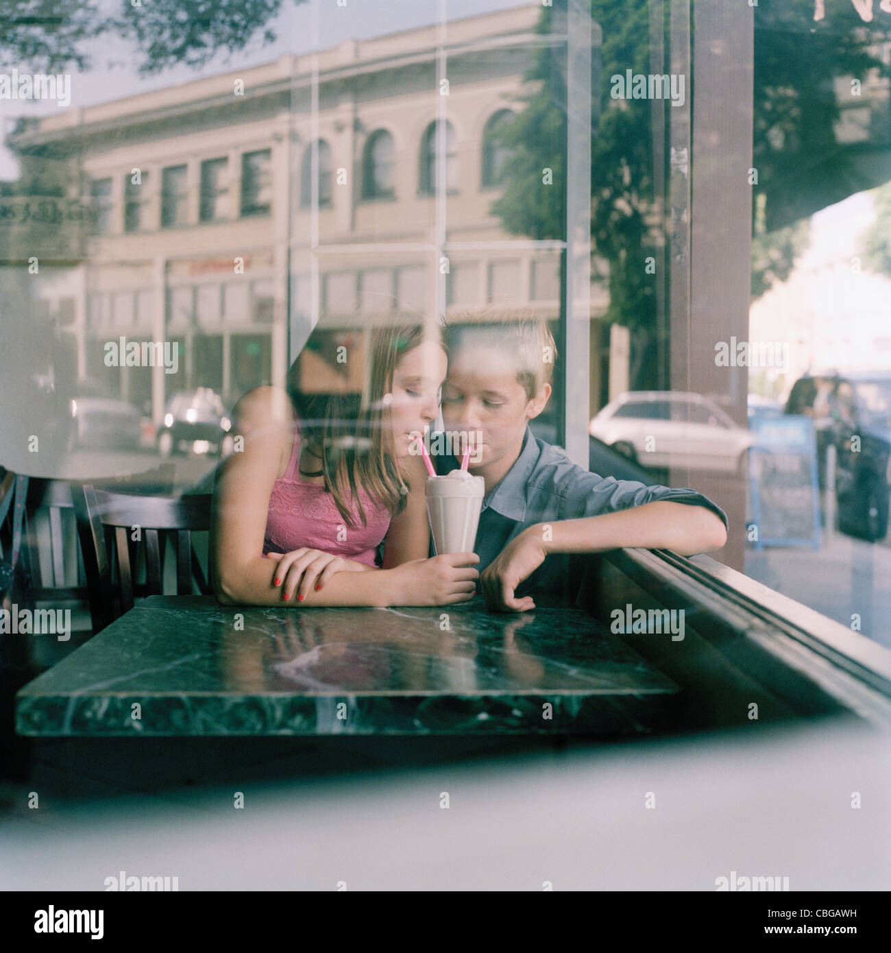 Ein junger Teenager Paar teilen einen Milchshake in einem Diner, angesehen durch Fenster Stockfoto