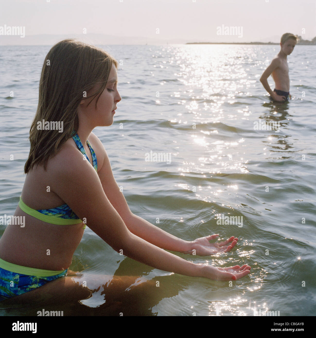 Ein junges Mädchen beim Waten im Meer auf dem Wasser schöpfen Stockfoto