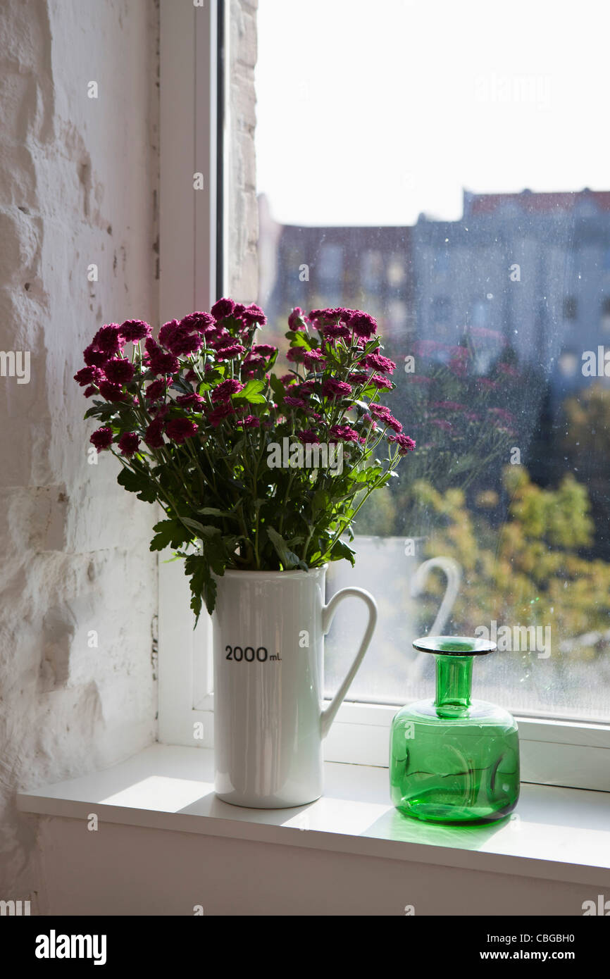 Eine grüne Flasche und Blumenstrauß auf dem Fensterbrett Stockfoto