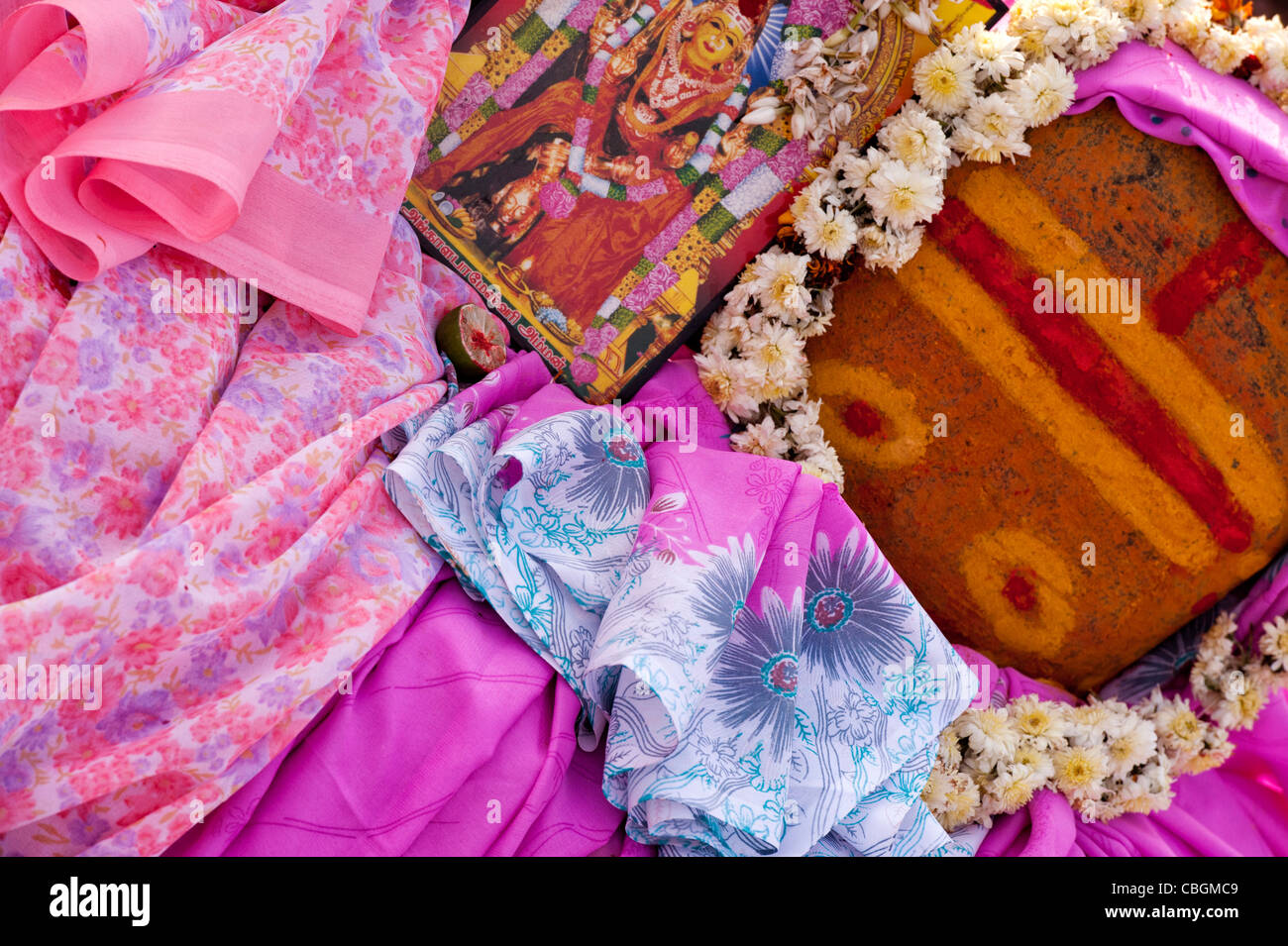 Weibliche hinduistischen Gottheit Tempel Heiligtum Stein mit Blumen Saris und ein Bild geschmückt. Indien Stockfoto