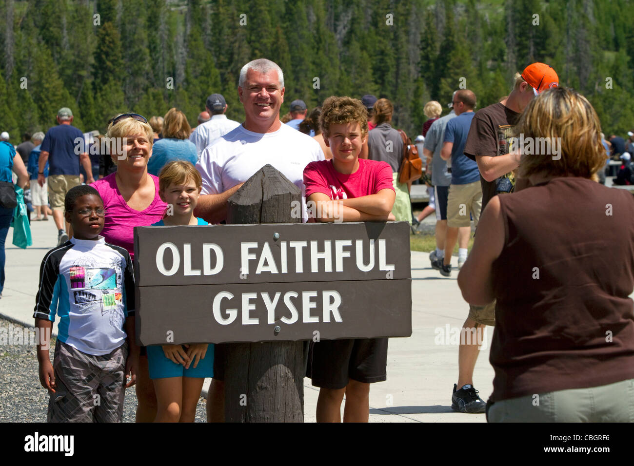 Touristen posieren für ein Foto im Old Faithful Geysir im Yellowstone-Nationalpark, Wyoming, USA. Stockfoto