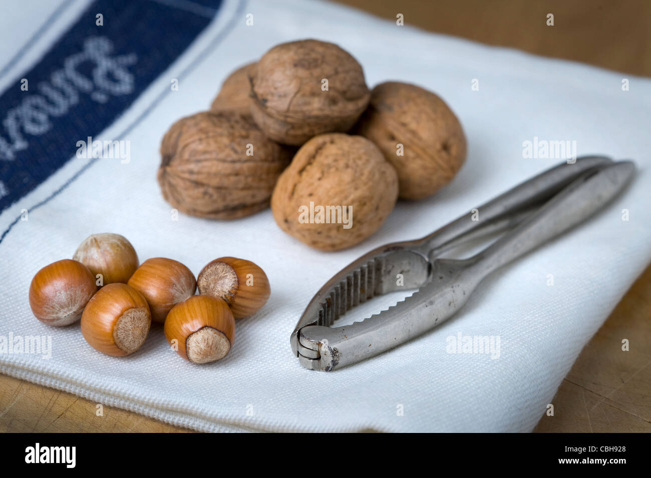 ganze Walnüsse und Haselnüsse auf einem weißen Tuch mit Nussknackern Stockfoto