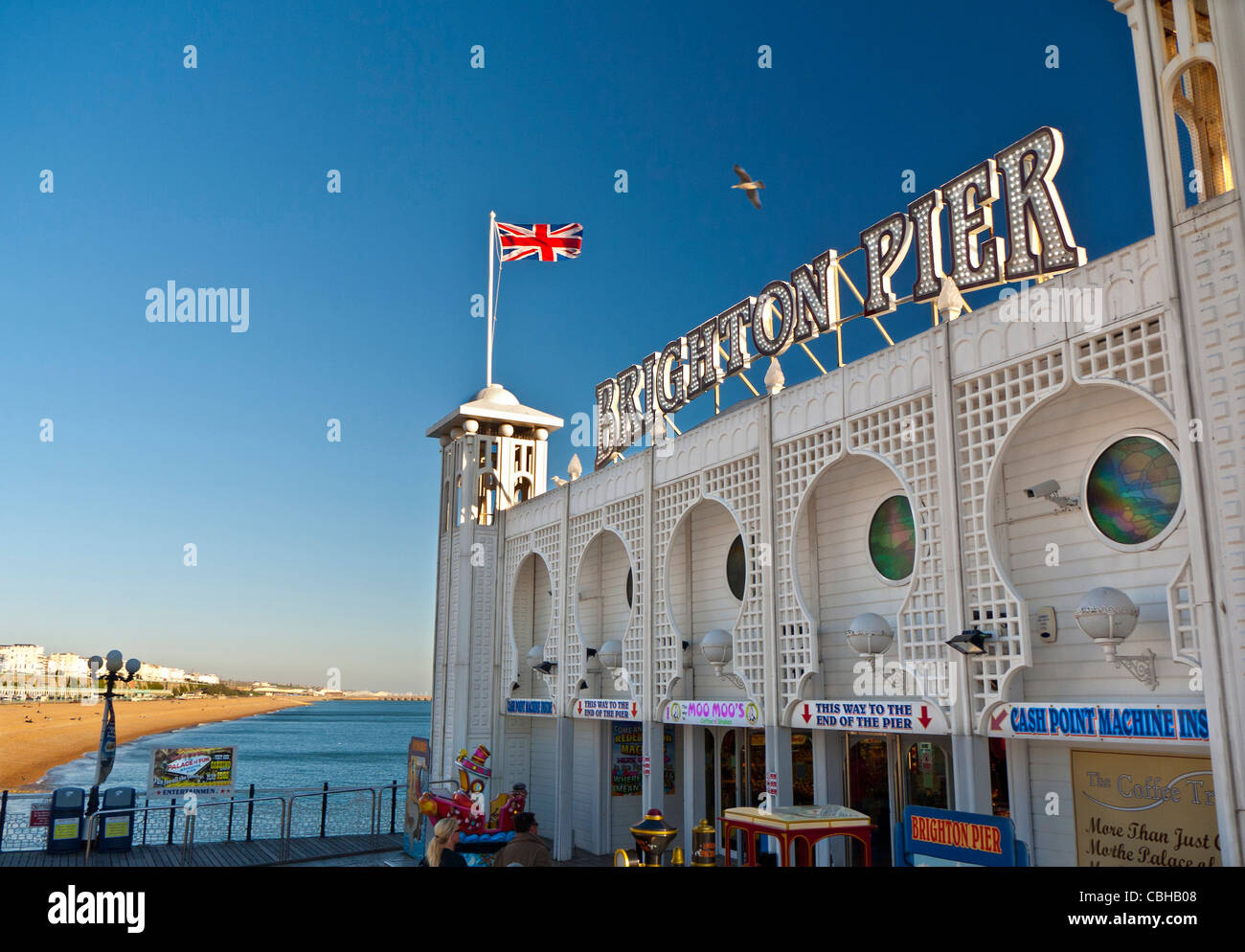 Brighton Pier Staycation mit Union Jack Flagge fliegen und sonnenbeschienenen Strand hinter Brighton West Sussex England Großbritannien Stockfoto
