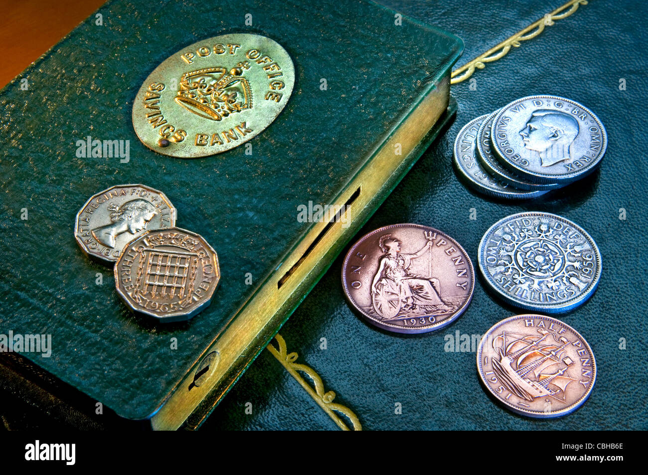 Pre-decimal UK Münzen und 50er Jahre Postamt Buch Spardose auf Schreibtisch Stockfoto