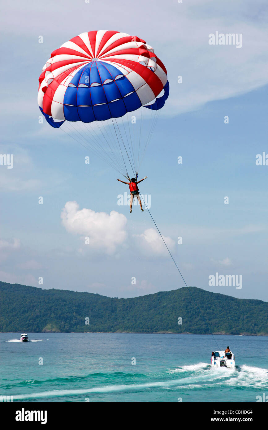 Touristen genießen Sie sportliche Aktivitäten, parasailing mit einem Schnellboot und Fallschirm auf Coral Island, Phuket, Thailand Stockfoto