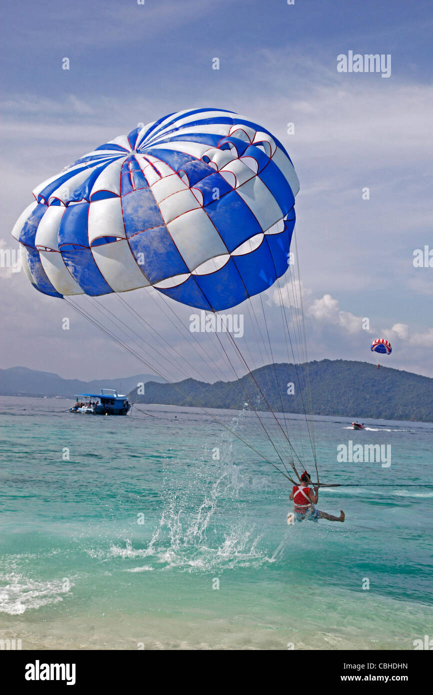 Touristen genießen Sie sportliche Aktivitäten, parasailing mit einem Schnellboot und Fallschirm auf Coral Island, Phuket, Thailand Stockfoto